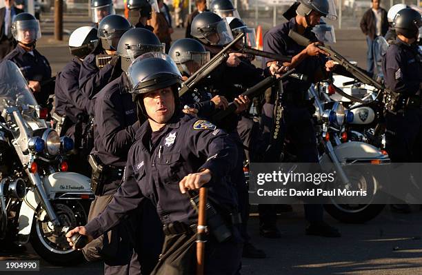 Riot police throw stun grenades and shoot rubber bullets at anti-war protesters as they block an entrance to the Oakland port April 7, 2003 in...