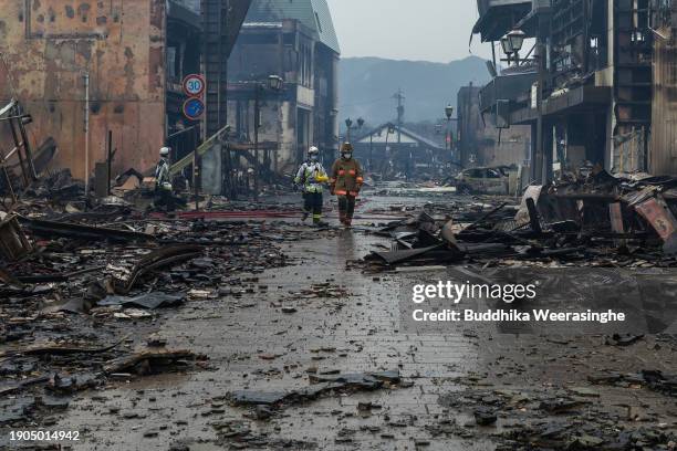 Firefighters walk near many buildings destroyed by fire after earthquakes on January 03, 2024 in Wajima, Japan. A series of major earthquakes have...