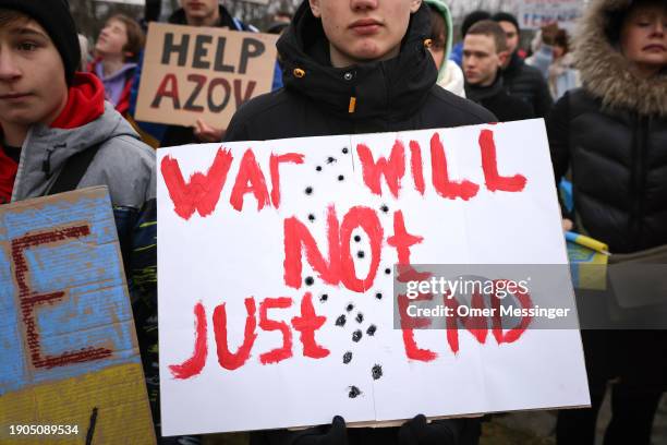 Protester holds a banner reading "War Will Not Just End" as activists from the German-Ukrainian group Vitsche protest outside the Chancellery to...