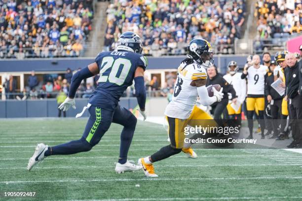 Diontae Johnson of the Pittsburgh Steelers tries to avoid Julian Love of the Seattle Seahawks after catching a pass at Lumen Field on December 31,...
