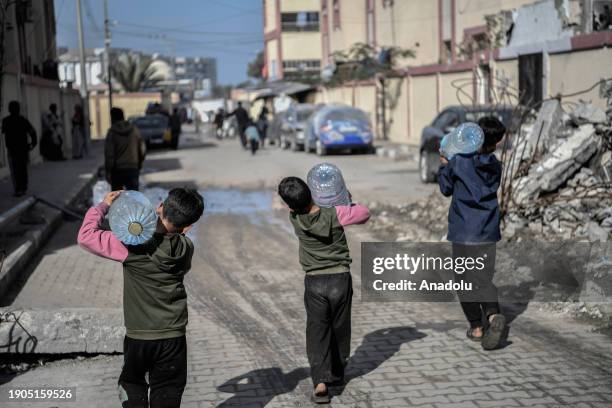 Palestinian children carry bottled water while Israel's attacks continue on Gaza Strip as Palestinians who took refuge in the city of Rafah are...