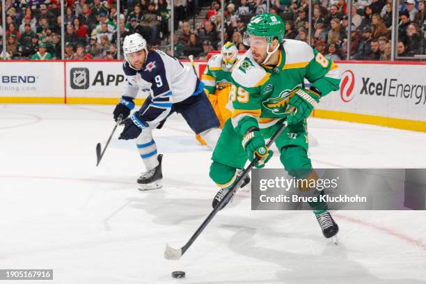 Frederick Gaudreau of the Minnesota Wild skates with the puck while Alex Iafallo of the Winnipeg Jets defends during the game at the Xcel Energy...