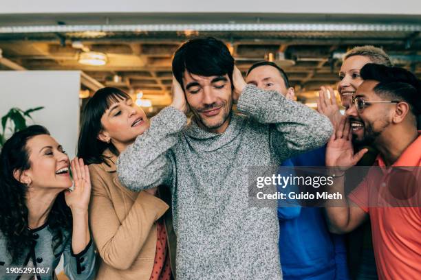 businessman with head in hands while other people talk to him in a coworking space. - bavardage photos et images de collection