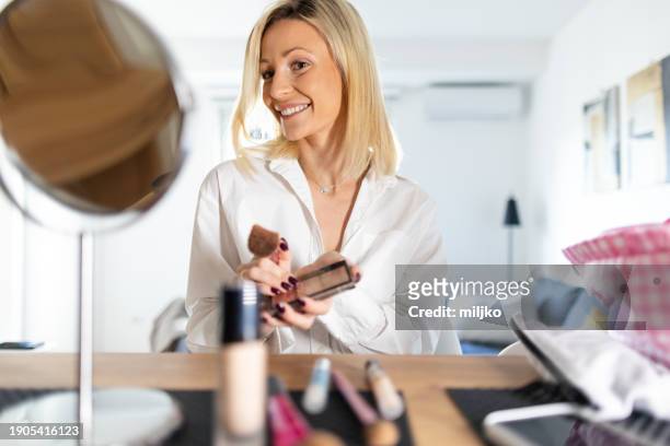 a beautiful young woman applying make up in her living room - correction fluid stock pictures, royalty-free photos & images