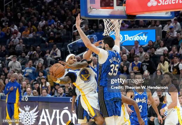 Gary Payton II of the Golden State Warriors driving to the basket shoots and scores over Goga Bitadze of the Orlando Magic during the third quarter...