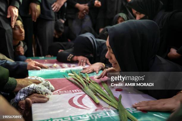 Kerman, Iran. Iranian family mourns next to coffins wrapped with the Iranian flags during the funeral ceremony of yesterday's explosion on January 5...