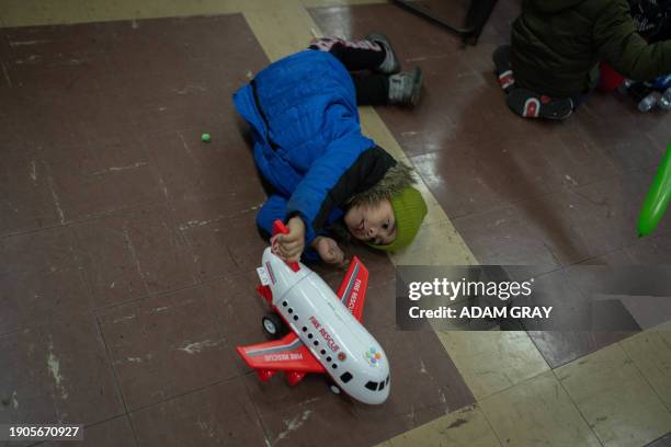 Migrant child plays with a toy airplane at a Three Kings Day celebration for migrants, offering free clothes, food and presents at Calvary United...