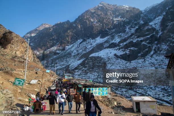 Indian tourists walk on the banks of a partially frozen Lidder river in southern Kashmir's famous tourist resort Pahalgam about 120km from summer...