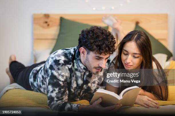 happy couple reading book on bed - closing book stock pictures, royalty-free photos & images