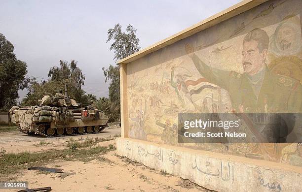Army 3rd Division 3-7 infantry Bradley fighting vehicle rolls past a Saddam Hussein mural as it conducts a neighborhood patrol on the outside...
