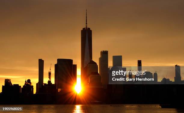 The sun rises behind the skyline of lower Manhattan and One World Trade Center in New York City on January 3 as seen from Jersey City, New Jersey.