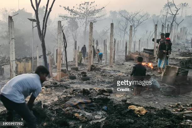 Rohingya refugees look through the debris of their houses charred by a devastating fire at the Ukhia camp, Cox's Bazaar in the early hours of January...