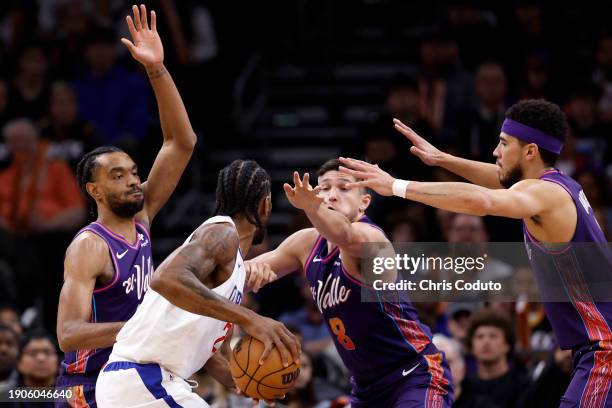 Keita Bates-Diop, Grayson Allen and Devin Booker of the Phoenix Suns defend Kawhi Leonard of the Los Angeles Clippers during the first half at...