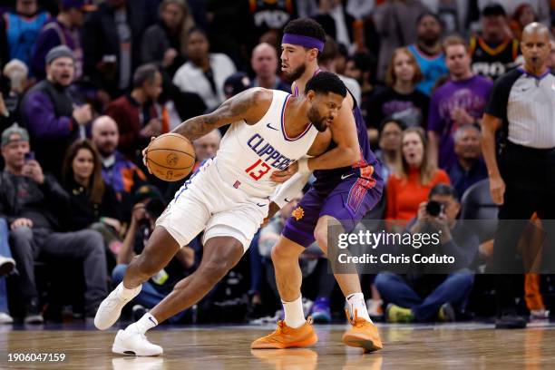 Paul George of the Los Angeles Clippers posts up against Devin Booker of the Phoenix Suns during the first half at Footprint Center on January 03,...