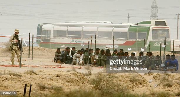 Soldier stands guard over Iraqi prisoners of war at Camp Bucca April 8, 2003 near Umm Qasr, Iraq. The Enemy Prisoner of War camp is currenty holding...