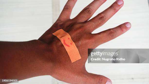 backhand palm with smile emoticon plaster - schnittwunde stock-fotos und bilder