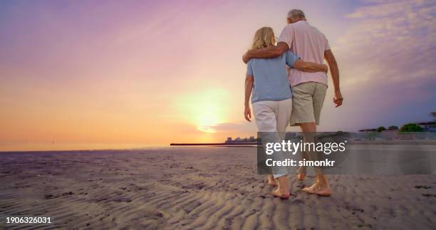 senior couple walking on beach - woman walking barefoot stock pictures, royalty-free photos & images