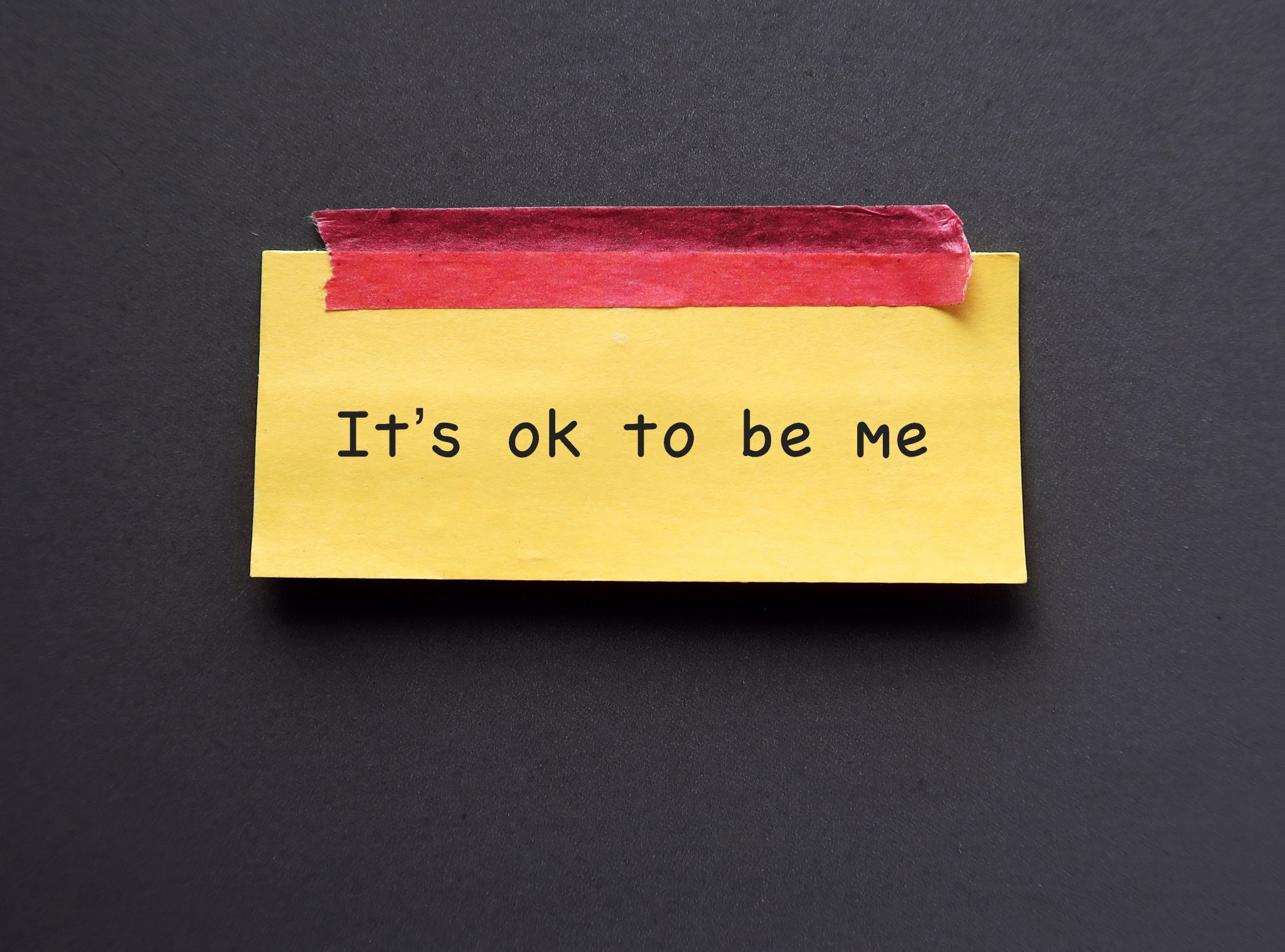 Yellow note stick on blue background with text 'Its ok to be me' concept of using positive sentences mantra affirmation will immediately change the way we think and boost self esteem Yellow note stick on blue background with text 'Its ok to be me' concept of using positive sentences mantra affirmation will immediately change the way we think and boost self esteem