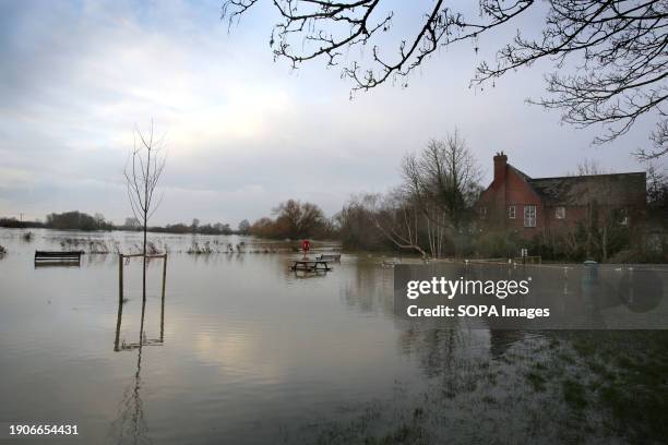 Water covers a car park and a footpath and surrounds benches and picnic tables as the River Great Ouse bursts its banks at Hartford. Flood alerts...