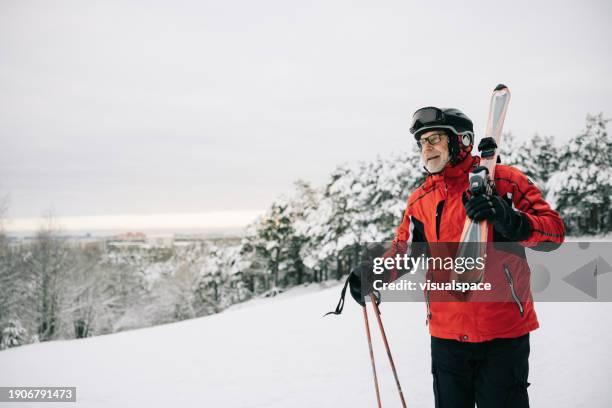 active senior man walks with skis on his shoulder - skiing and snowboarding stock pictures, royalty-free photos & images