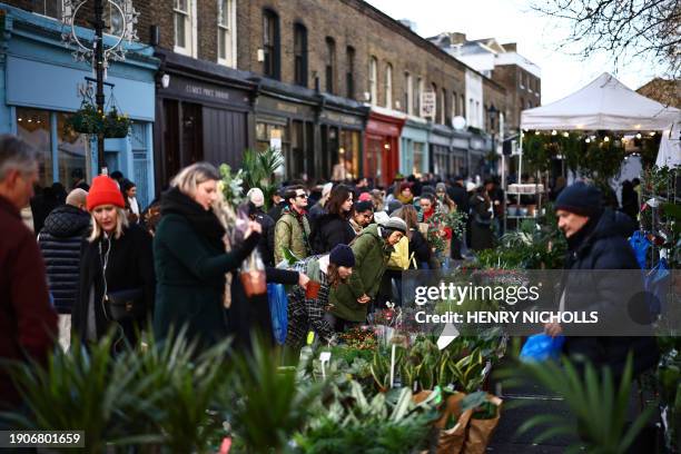 Customers buy flowers on stalls at Columbia Road Flower Market, in east London on January 7, 2024.