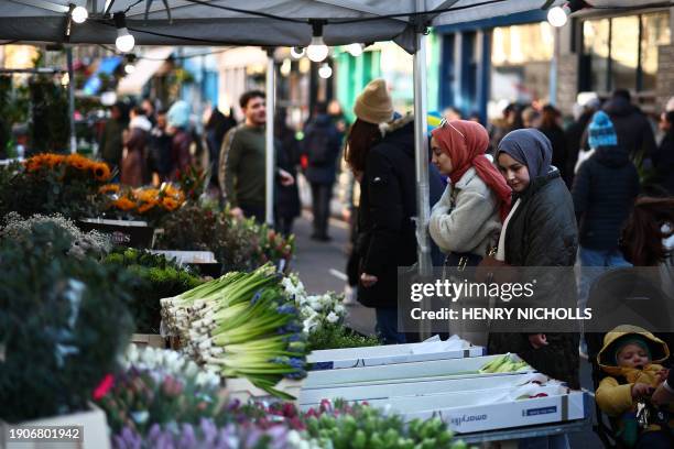 Customers buy flowers on stalls at Columbia Road Flower Market, in east London on January 7, 2024.