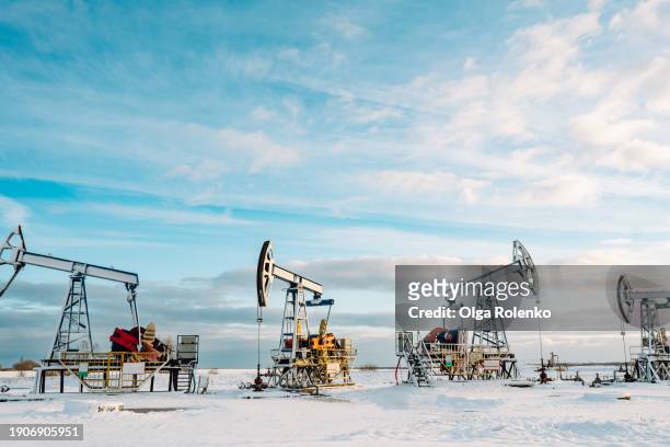 exploration and exploitation of natural gas and oil in cold north area. two oil jacks pumps working in winter season - working oil pumps stockfoto's en -beelden