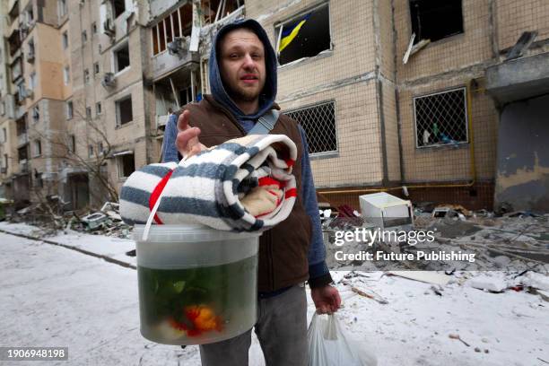 Man carries a bucket with goldfish rescued from an apartment building in the Solomianskyi district destroyed in the Russian missile attack on...