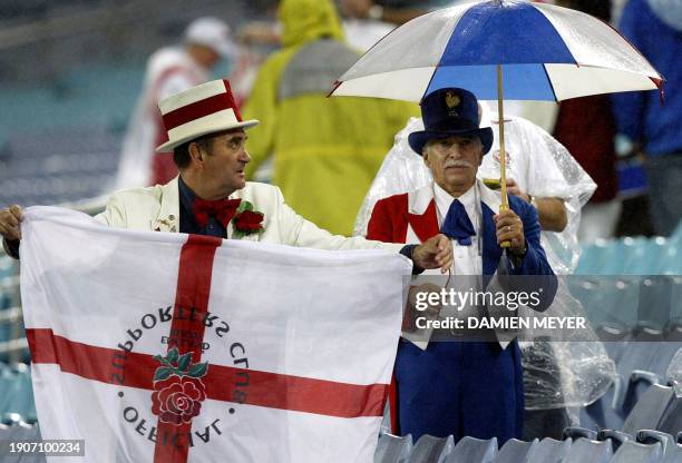 French fan looks dejected while an English one waves a flag after the Rugby World Cup semi-final match between France and England, 16 November 2003...