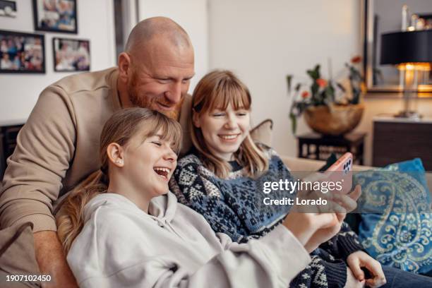 father and daughters using streaming devices at home - dutch family stockfoto's en -beelden