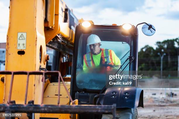 construction worker operating heavy machinery at jobsite - construction machinery stock pictures, royalty-free photos & images