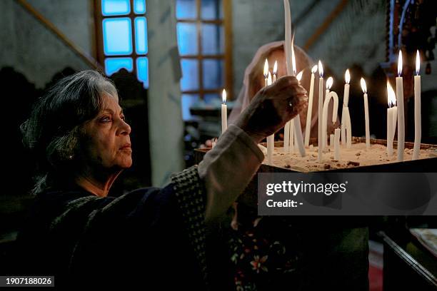 An Orthodox worshipper lights candles during a mass at the Greek Orthodox Church of Saint Porphyrius in Gaza City on January 7, 2024 amid the ongoing...