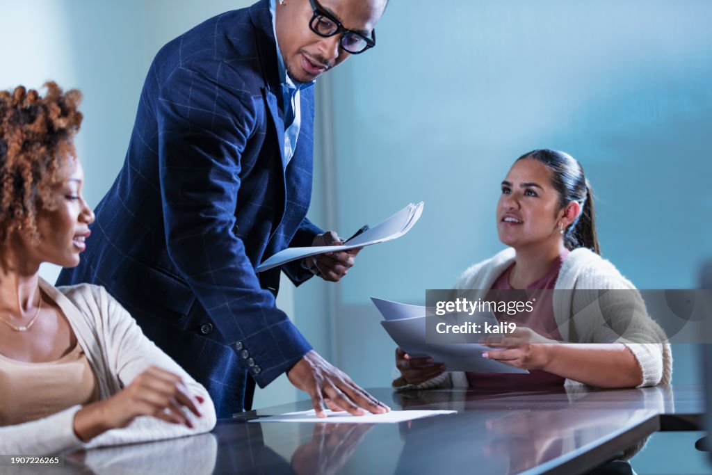 African-American businessman hands out papers in meeting