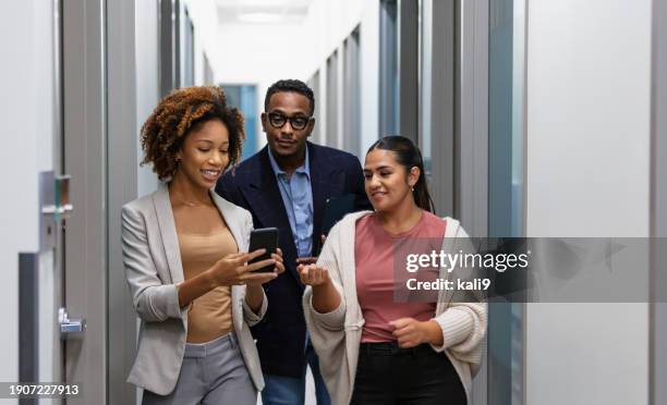 multiracial office workers in hallway with mobile phone - maschio con gruppo di femmine foto e immagini stock