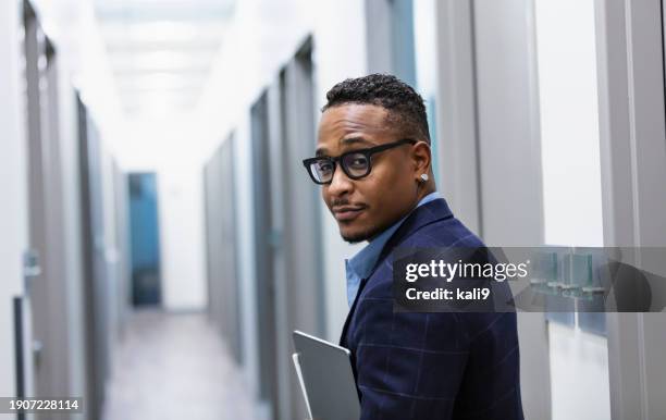 homme d’affaires afro-américain marchant dans un couloir - regarder par dessus son épaule photos et images de collection