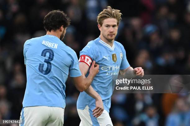 Manchester City's Portuguese defender Ruben Dias passes the captain's armband to Manchester City's Belgian midfielder Kevin De Bruyne during the...