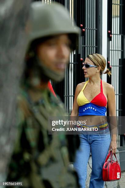 Una opositora al mandatario Hugo Chávez, luciendo los colores de la bandera venezolana, aguarda su turno frente a un centro recoletor de firmas para...