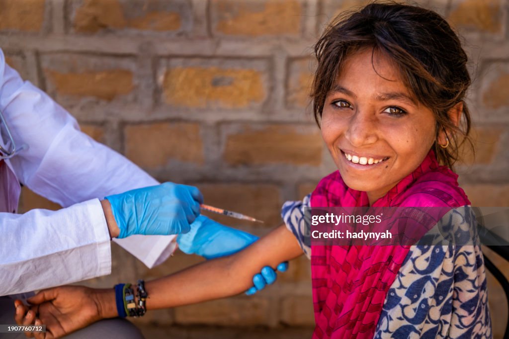Female doctor is doing an injection to young Indian girl in small village