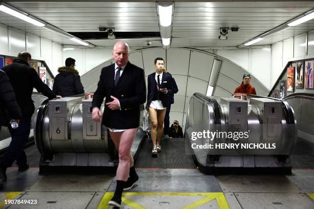 People taking part in the annual "No Trousers On The Tube Day" , walk in a metro station of the London Underground, in London, on January 7, 2024....