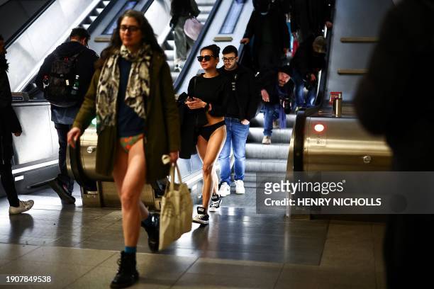 People taking part in the annual "No Trousers On The Tube Day" , walk in a metro station of the London Underground, in London, on January 7, 2024....