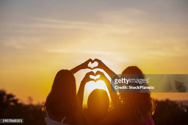 filles faisant une forme de coeur avec leurs mains - geste de la main photos et images de collection