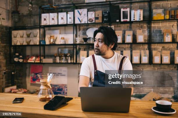 japanese business owner working with laptop in his coffee shop - entrepreneur stockfoto's en -beelden