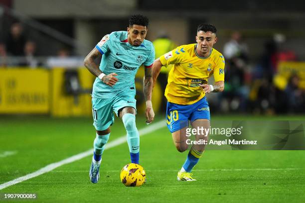 Raphinha of FC Barcelona runs with the ball whilst under pressure from Alberto Moleiro of UD Las Palmas during the LaLiga EA Sports match between UD...