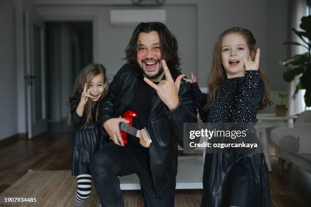 happy daughters dancing while father playing on guitar - músico de rock imagens e fotografias de stock