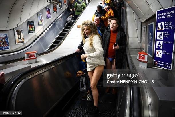 People taking part in the annual "No Trousers On The Tube Day" , walk in a metro station of the London Underground, in London, on January 7, 2024....