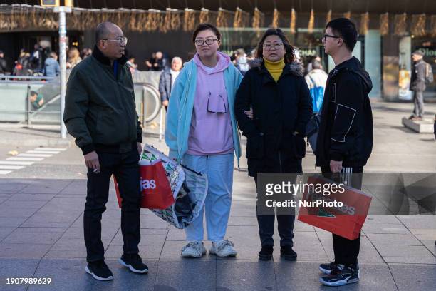 Family of Asian tourists is taking advantage of their vacation and shopping in the city center on the first day of winter sales in Barcelona, Spain,...