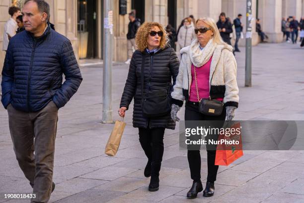 Two women are walking with bags through the Portal del Angel on the first day of winter sales in Barcelona, Spain, on January 7, 2024. The Portal del...