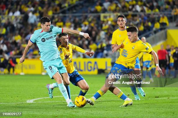 Robert Lewandowski of FC Barcelona battles for possession with with Mika Marmol and Maximo Perrone of UD Las Palmas during the LaLiga EA Sports match...