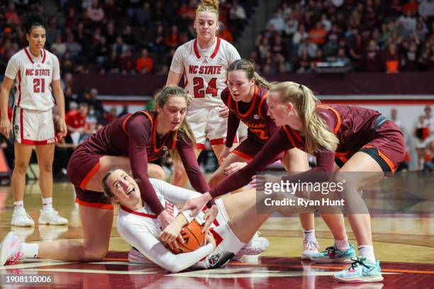 Members of the Virginia Tech Hokies reach in for a loose ball guarded by Lizzy Williamson of the NC State Wolfpack in the first half during a game at...