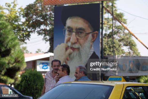 Yellow cab drivers are standing together under a massive portrait of Iran's Supreme Leader, Ayatollah Ali Khamenei, in northern Tehran, Iran, on...